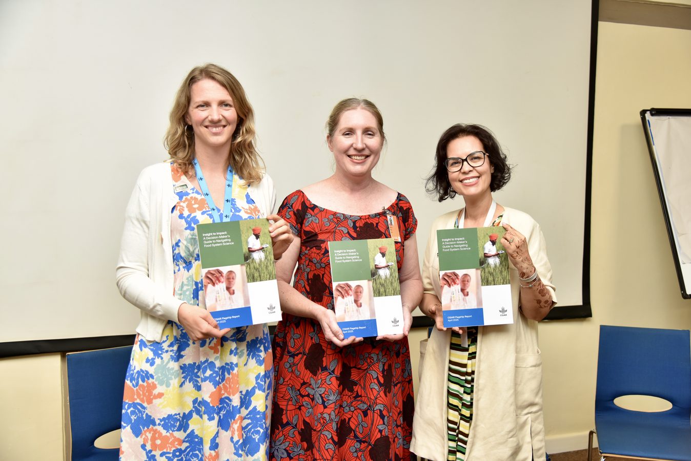 Three colleagues holding copies of a CGIAR flagship report